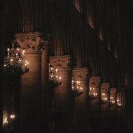 the exterior of another old building. there are pillars every few feet and each pillar has a lantern chandelier attached.